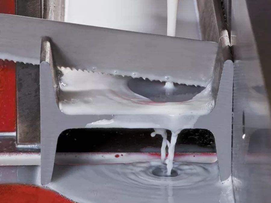 Band saw blade cutting through a steel beam with coolant flowing