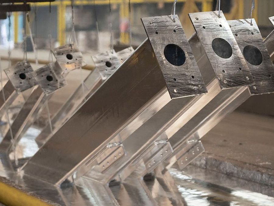 Freshly hot-dip galvanized steel members hanging above the kettle