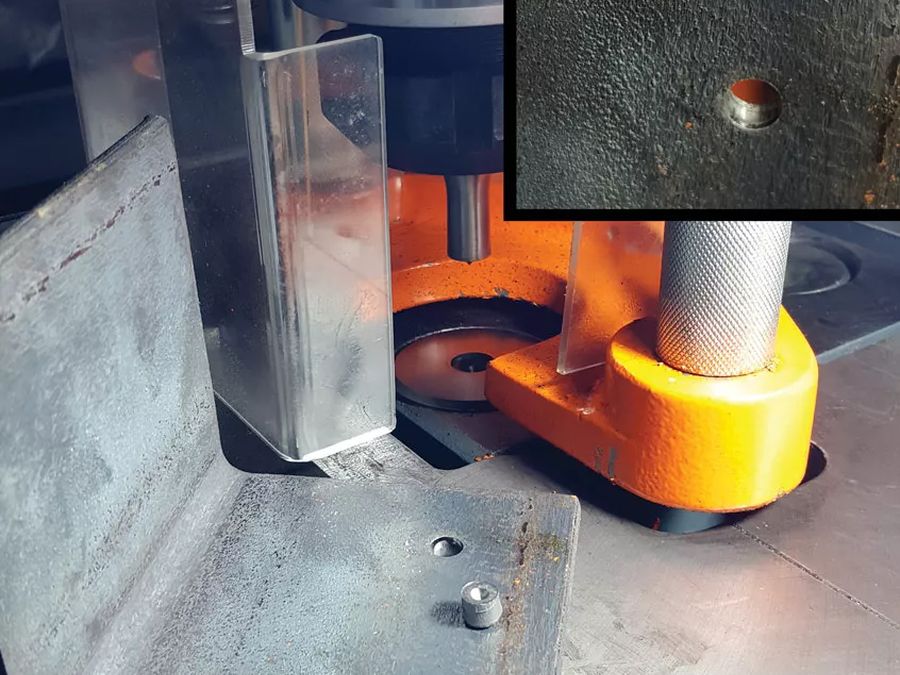 Ironworker punch driving a clean hole through steel angle